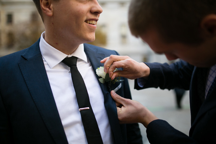 groom getting boutonniere pinned on