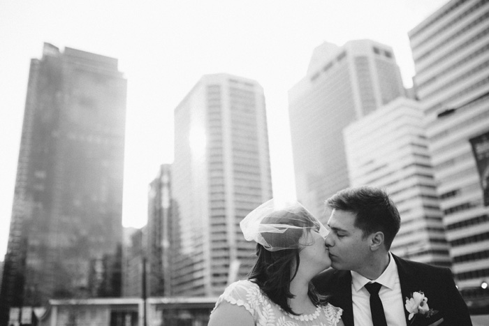 bride and groom kissing in front of cityscape