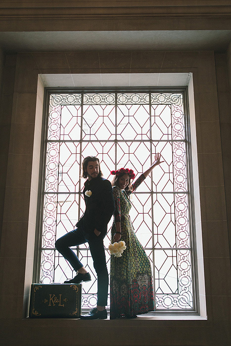 Bride and groom standing inside City Hall window