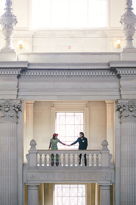 bride and groom hoding hands on second level of San Francisco City Hall