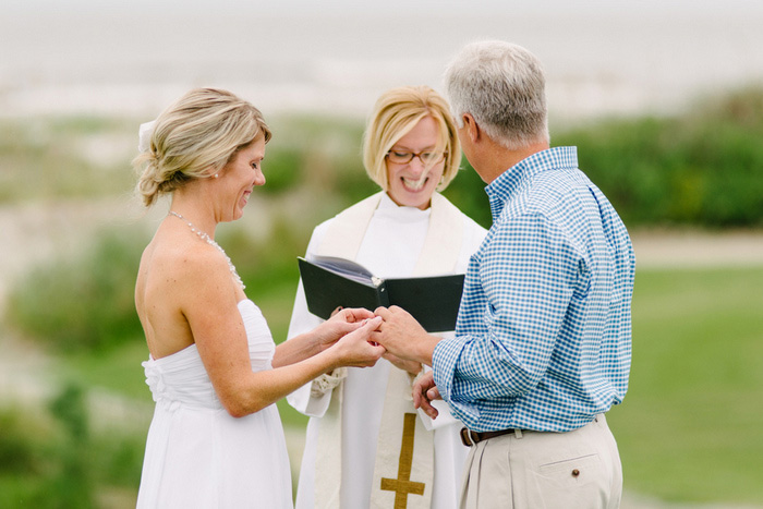 bride putting ring on groom's finger