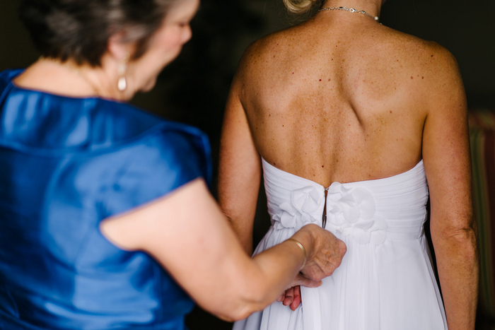 bride getting her dress zipped up