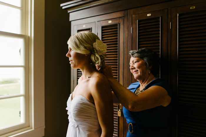 mother of the bride putting bride's necklace on her