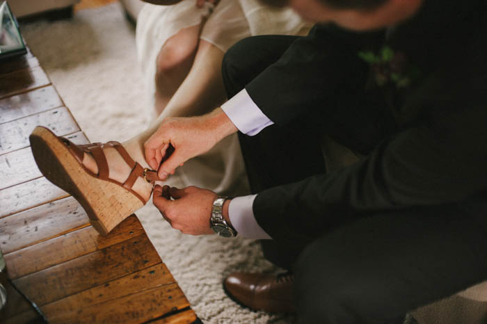 groom helping bride with her sandals