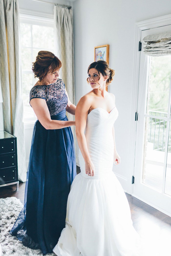 mother of the bride helping bride getting dressed