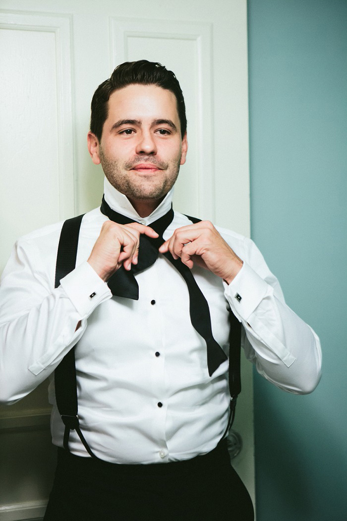 groom tying bow tie