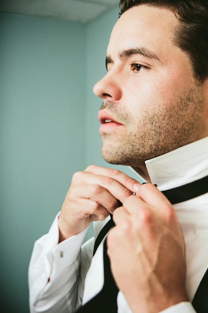 groom tying bow tie