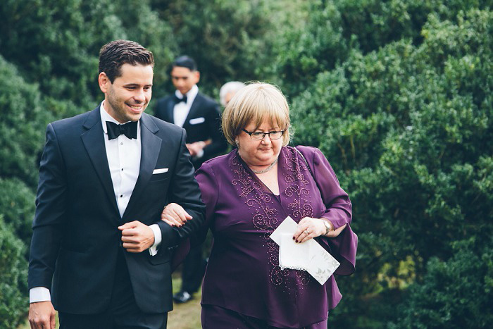 groom walking down aisle with his mother