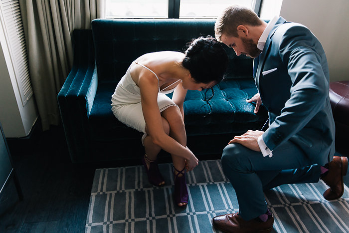 groom helping bride with her shoes