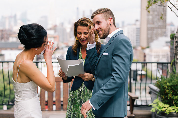 bride and groom wiping away tears during ceremony