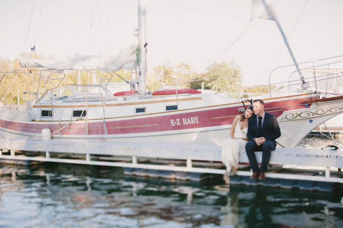 bride and groom sitting on the dock