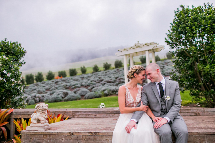 bride and groom sitting on stone wall