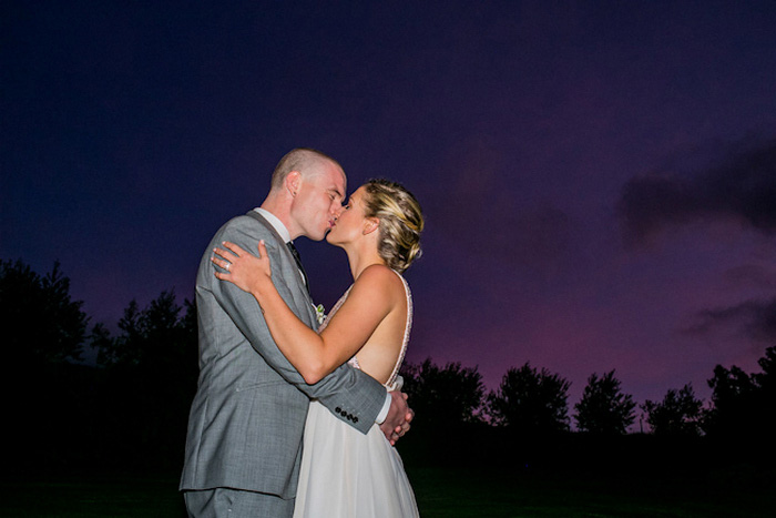 bride and groom kissing under Maui sky