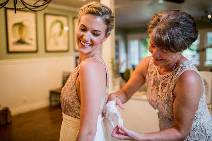 mother tying bow on bride's dress