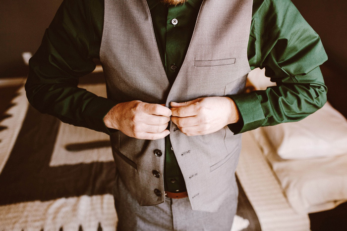 groom buttoning his vest