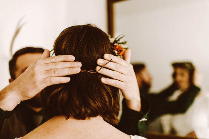 groom helping bride with floral crown