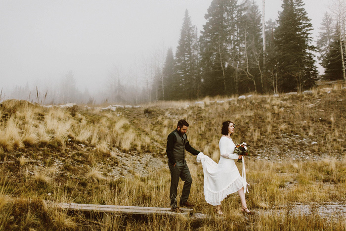 bride and groom walking through woods