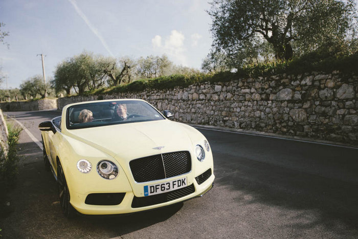 bride and groom driving in convertible 