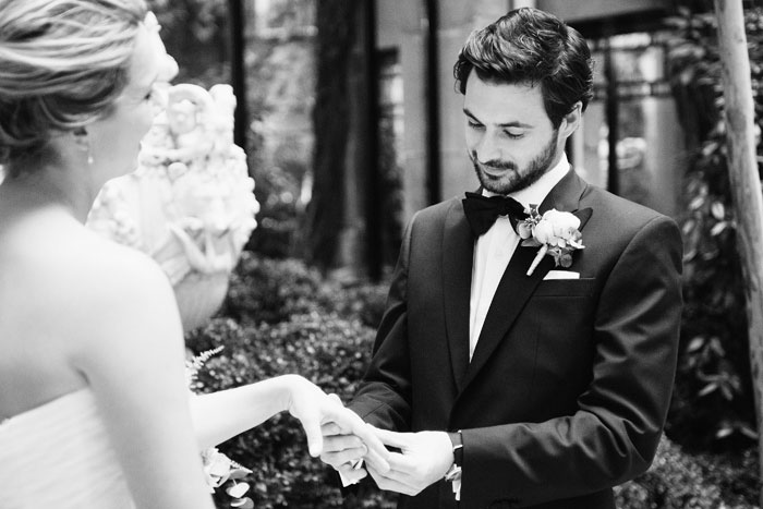 groom putting ring on bride's finger