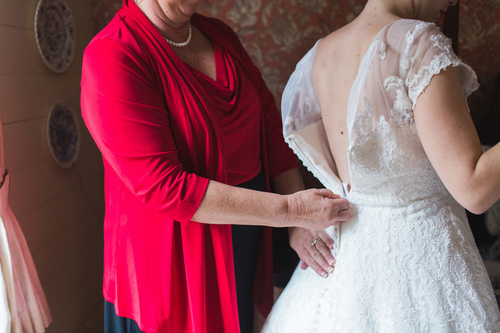 bride having dress zipped up