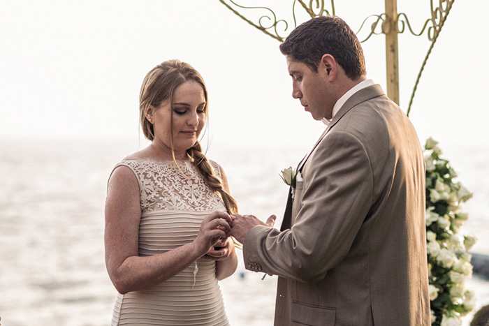 bride putting ring on groom's finger