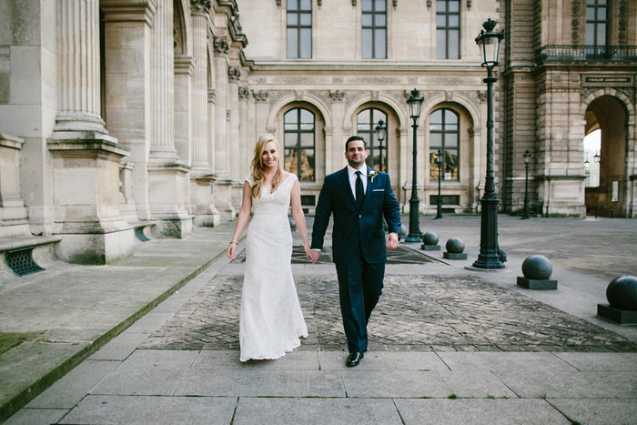 Bride and groom walking away from the Louvre