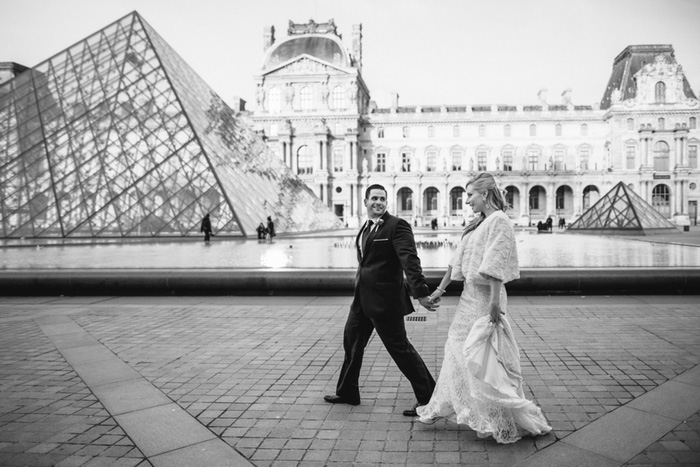 bride and groom walking by the Louvre