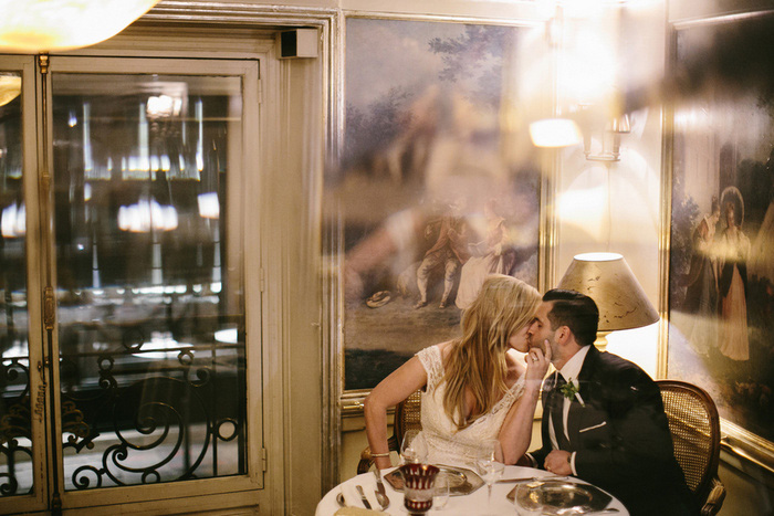 bride and groom kissing in Paris bistro