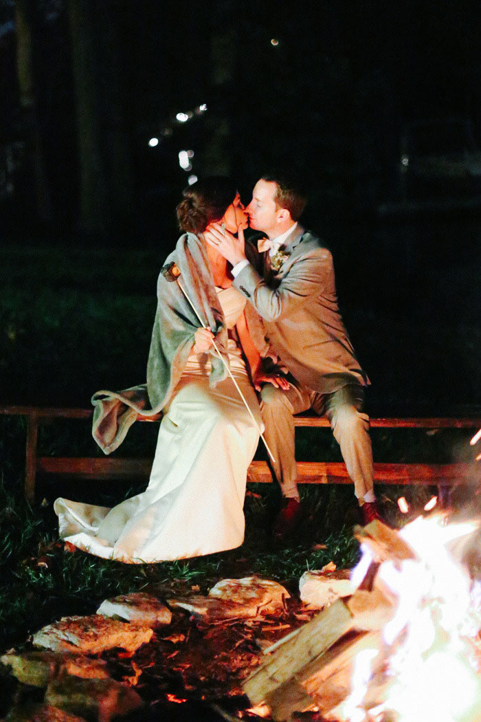 bride and groom kissing by bonfire