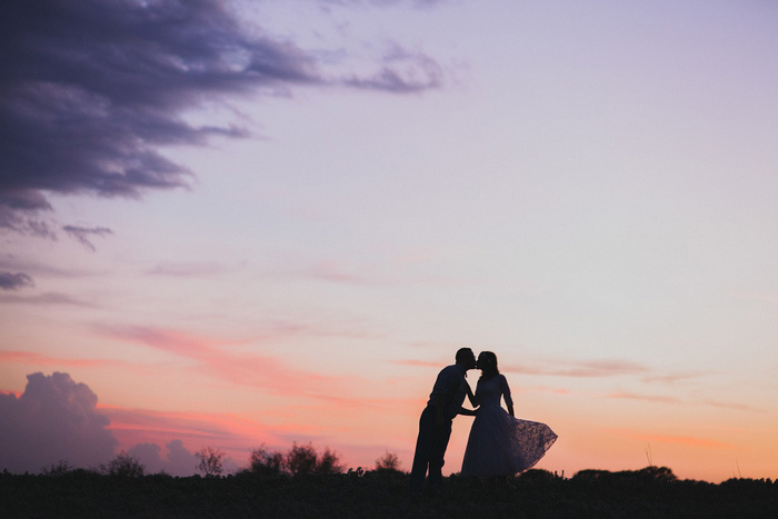 bride and groom kissing at sunset