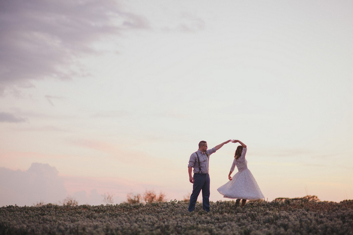 bride and groom dancing in a field