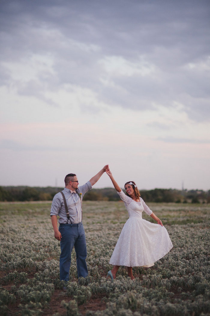 bride and groom dancing in field