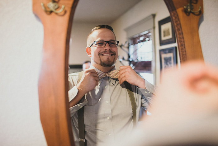 groom tying bow tie