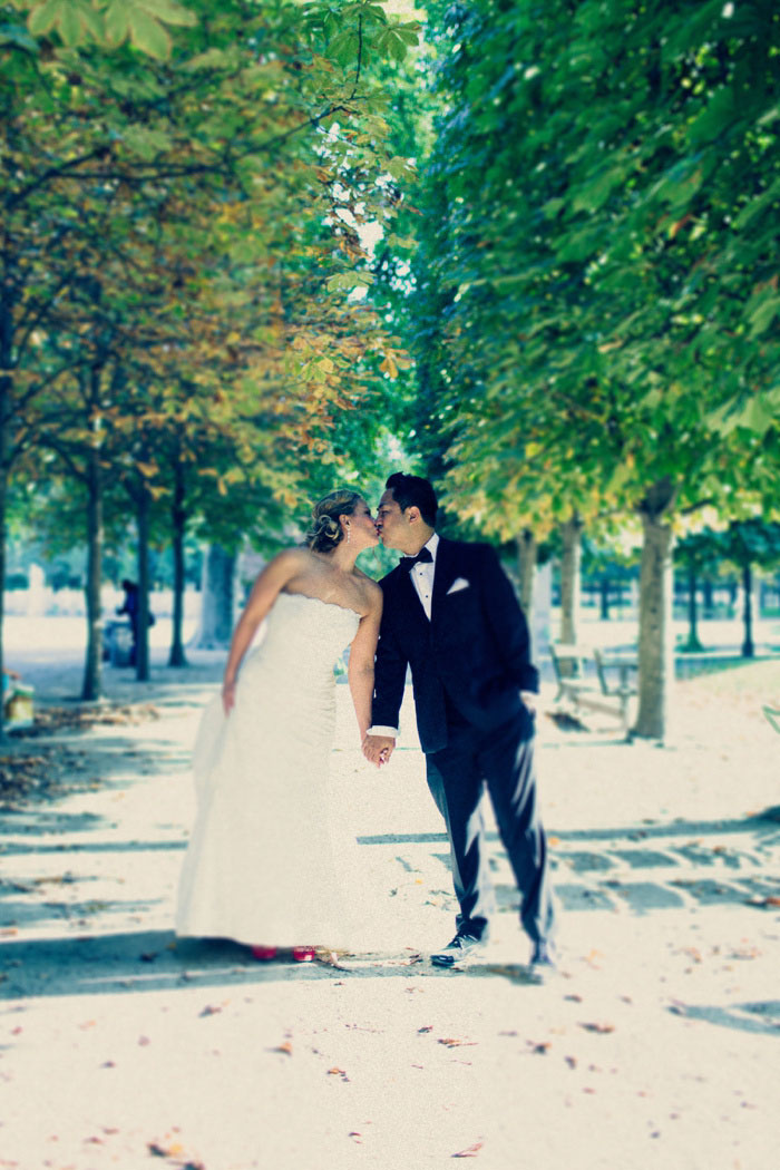 bride and groom kissing on treed walkway