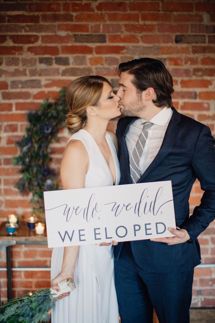 bride and groom holding we eloped sign