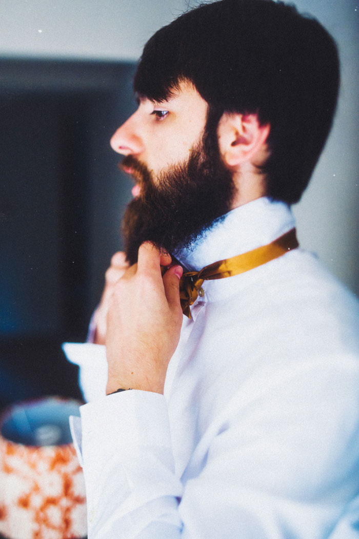 groom tying bow tie