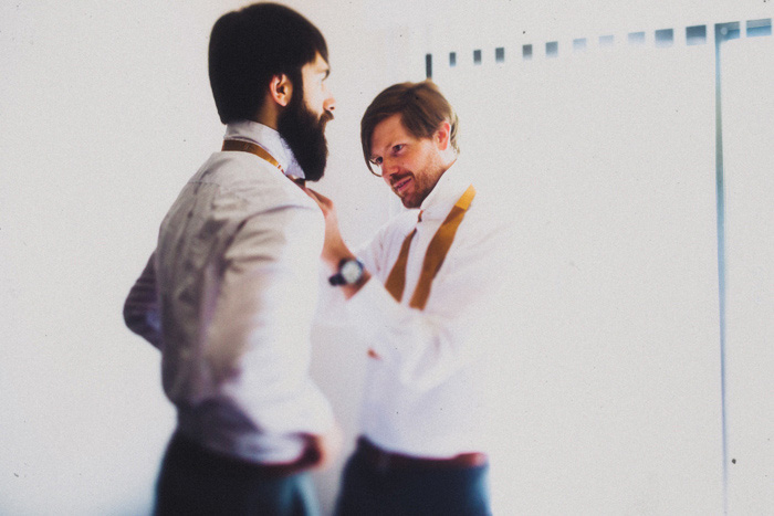 groomsman helping groom with bow tie