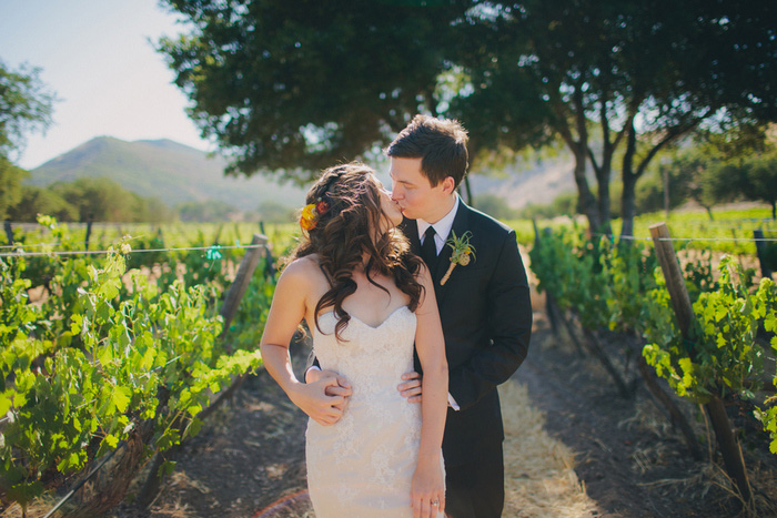 bride and groom kissing in vineyard