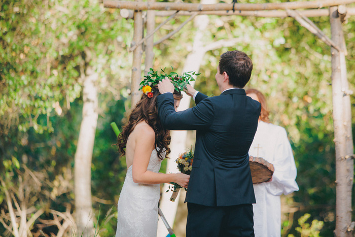 groom placing flower crown on bride's head