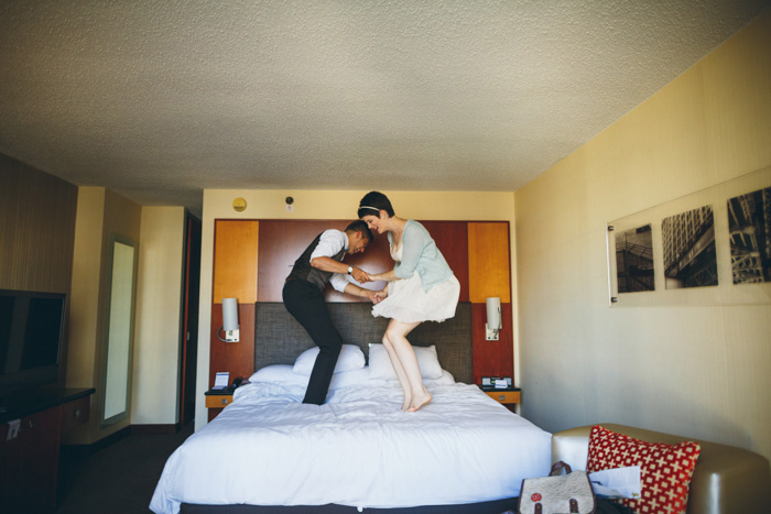 bride and groom jumping on the bed