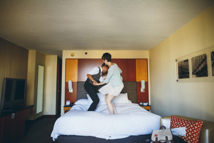 bride and groom jumping on the bed