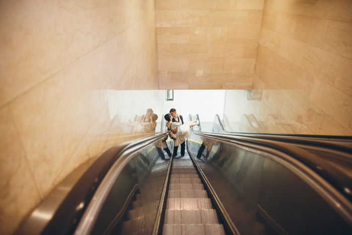 groom carrying bride on escalator