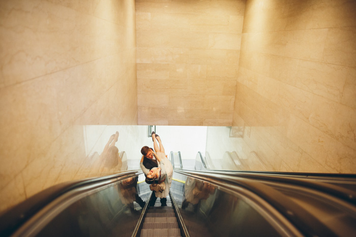 groom carrying bride on escalator