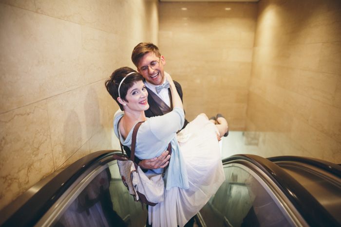 groom carrying bride on escalator