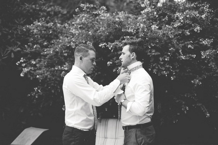 groomsman helping groom with tie