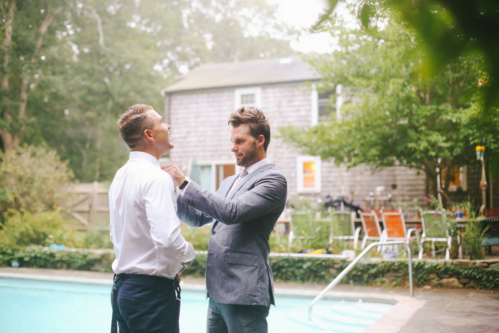 groom helping groomsman with tie