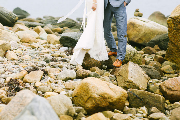 bride and groom standing on rocks