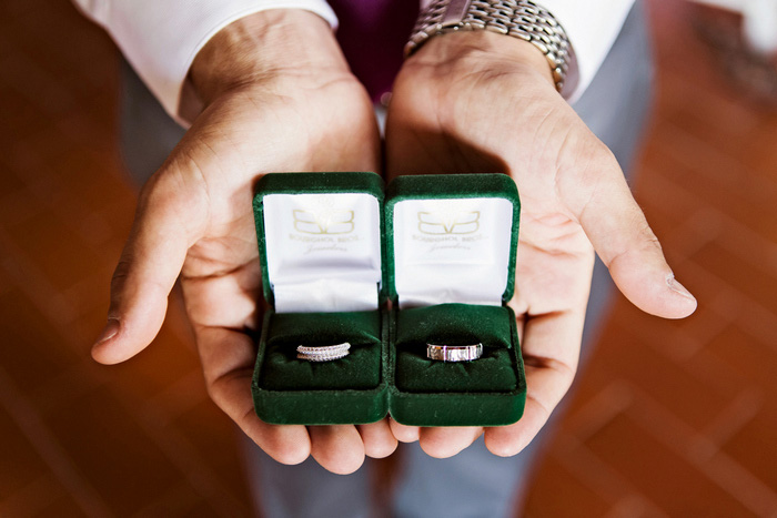 groom holding wedding rings