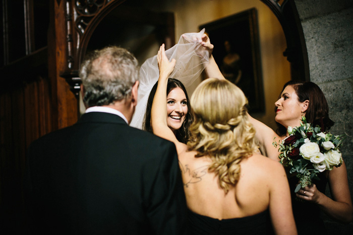 bridesmaids pulling bride's veil over her head