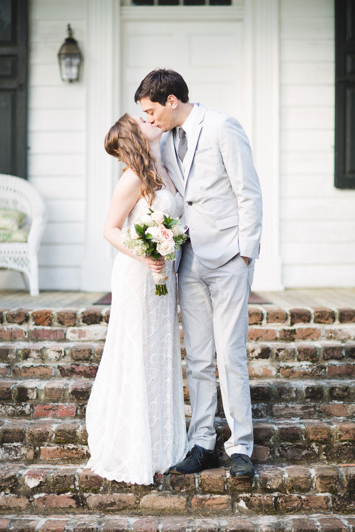 bride and groom kissing in front of porch